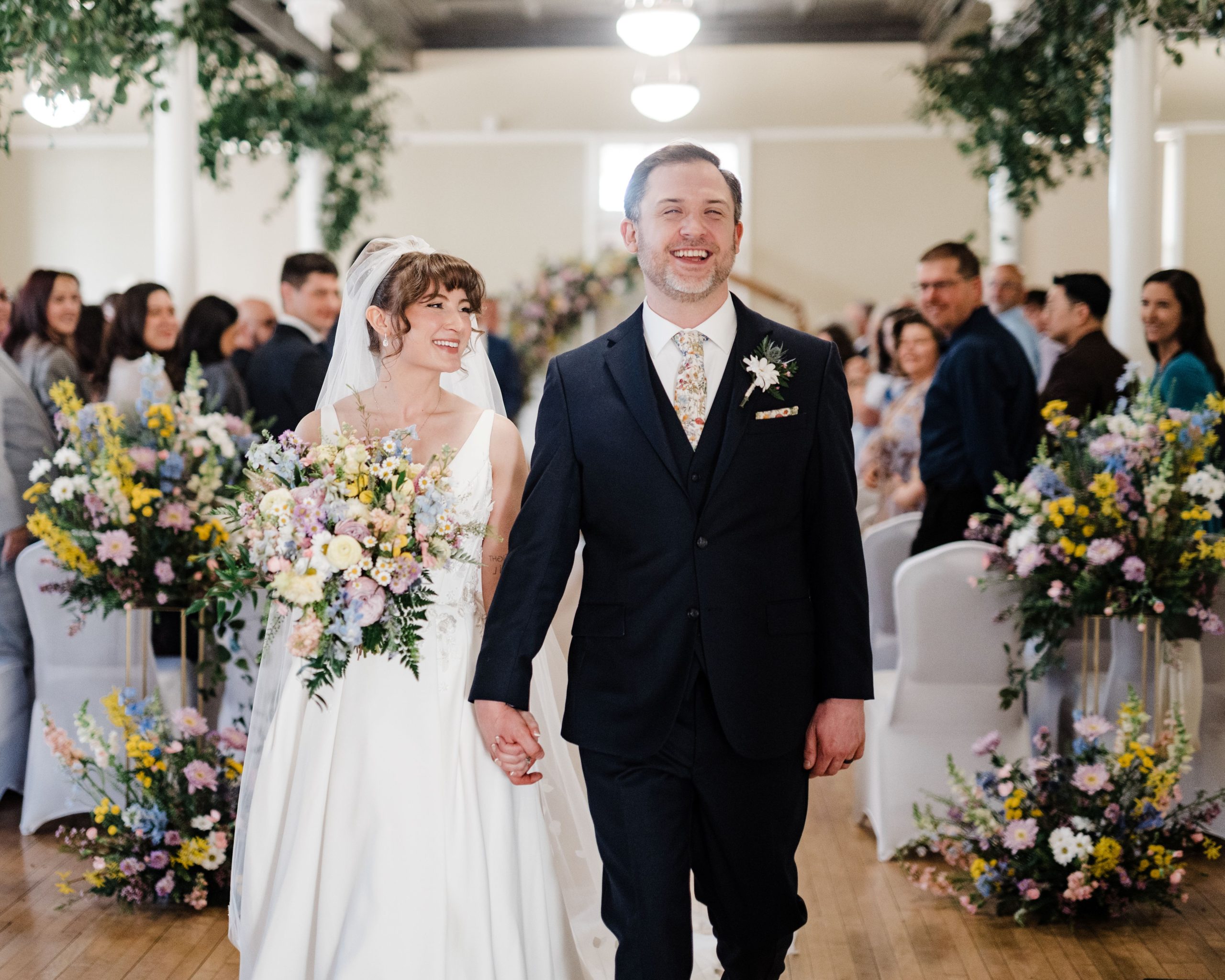 Amanda and Quintin Wedding Bride and groom in the aisle with pastel floral displays flanking the aisles