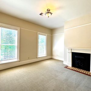 Larger bedroom with two windows and fireplace.